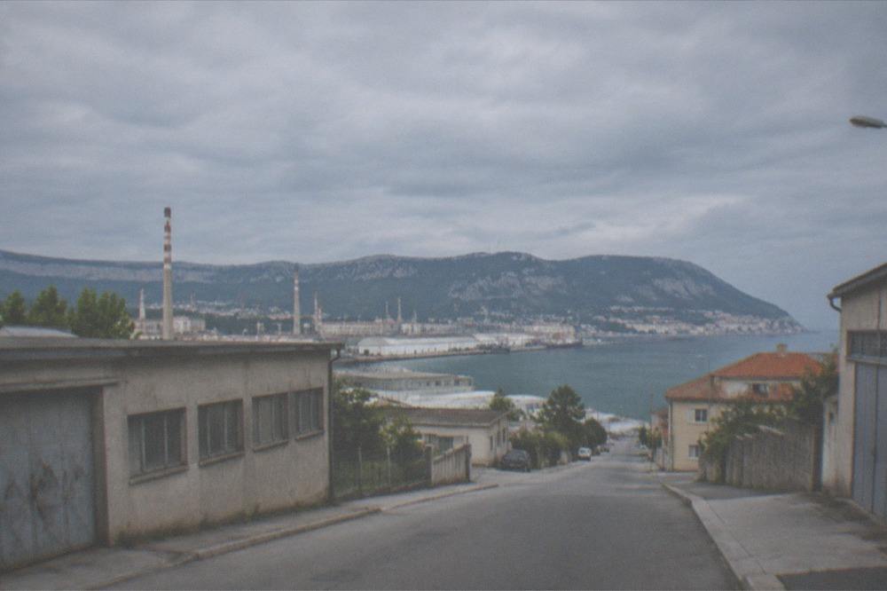 Low industrial buildings on two sides of an empty street in the Servola district of Trieste.