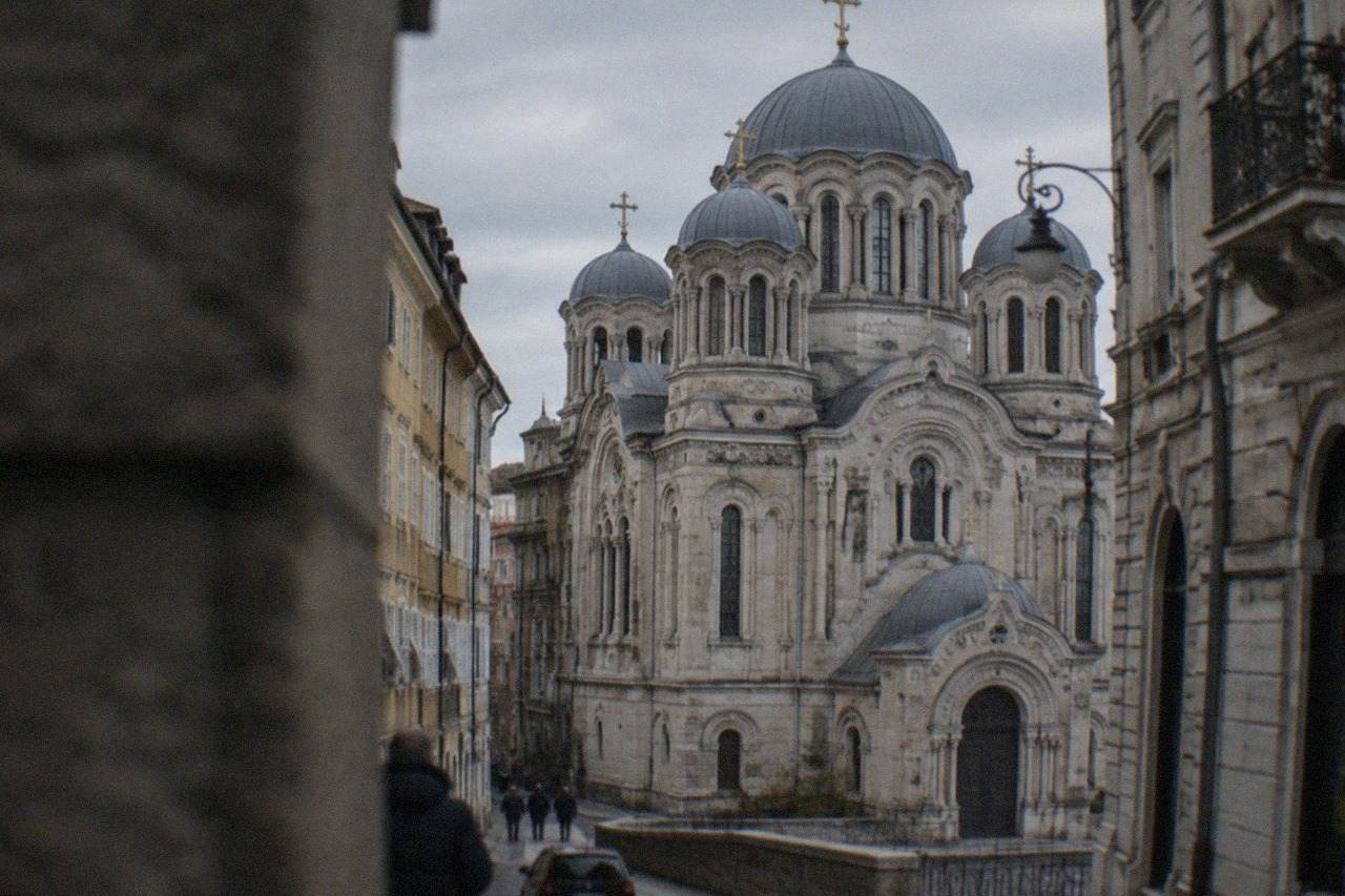 The ornate facade of the Saint Spyridon Serbian Orthodox Church standing above the narrow streets of Trieste's old town