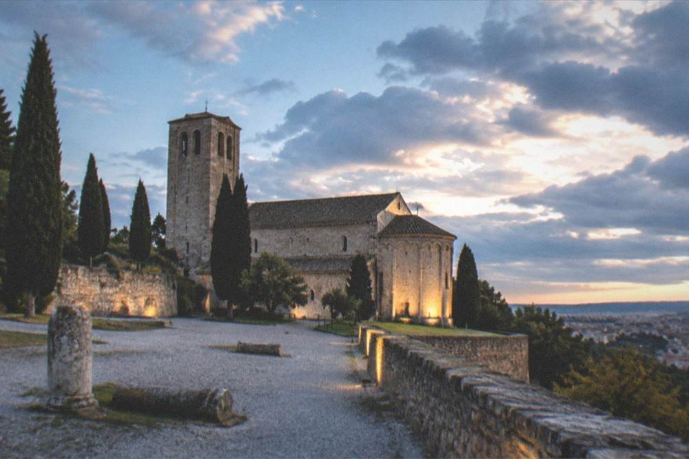 Evening light on the castle walls of San Giusto with the floodlit cathedral apse beyond