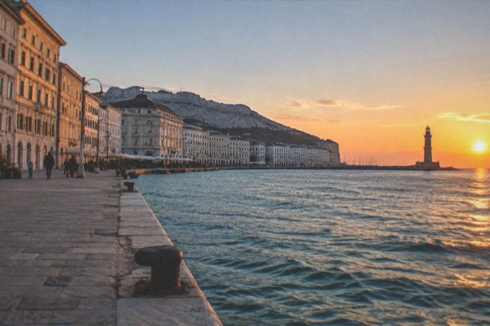 Evening light over the Trieste seafront with the lighthouse silhouette against the sky