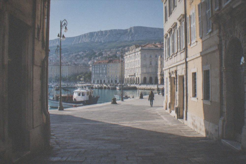 A stone coastal old town on a peninsula with fishing boats moored in a small harbour