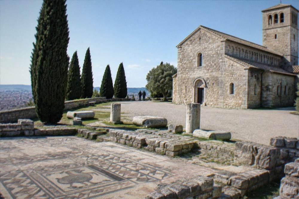 An ancient Roman mosaic floor with geometric and figurative patterns inside a stone basilica