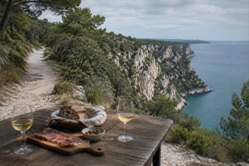 A rustic farmhouse table set with wine glasses, bread and cured meat