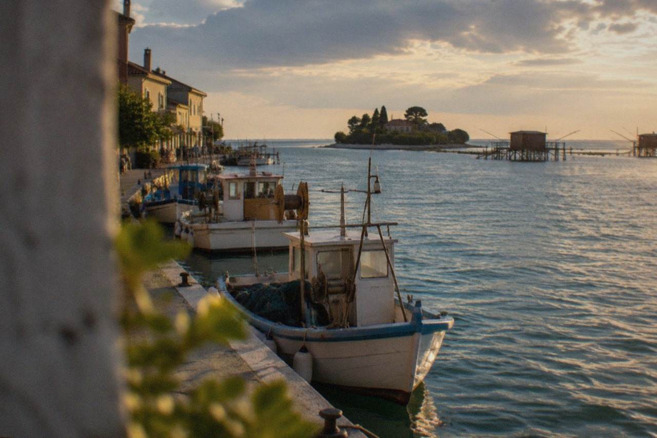 Fishing boats moored in a lagoon channel beside a small island town at golden hour