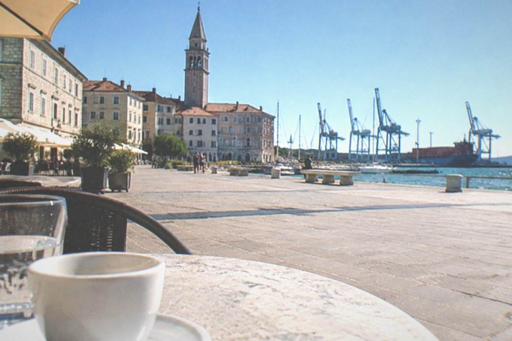 Sunny square with cafe tables and stone buildings under a clear sky