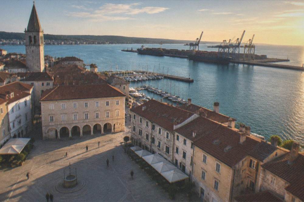 Evening light over a harbour with a town skyline and calm water