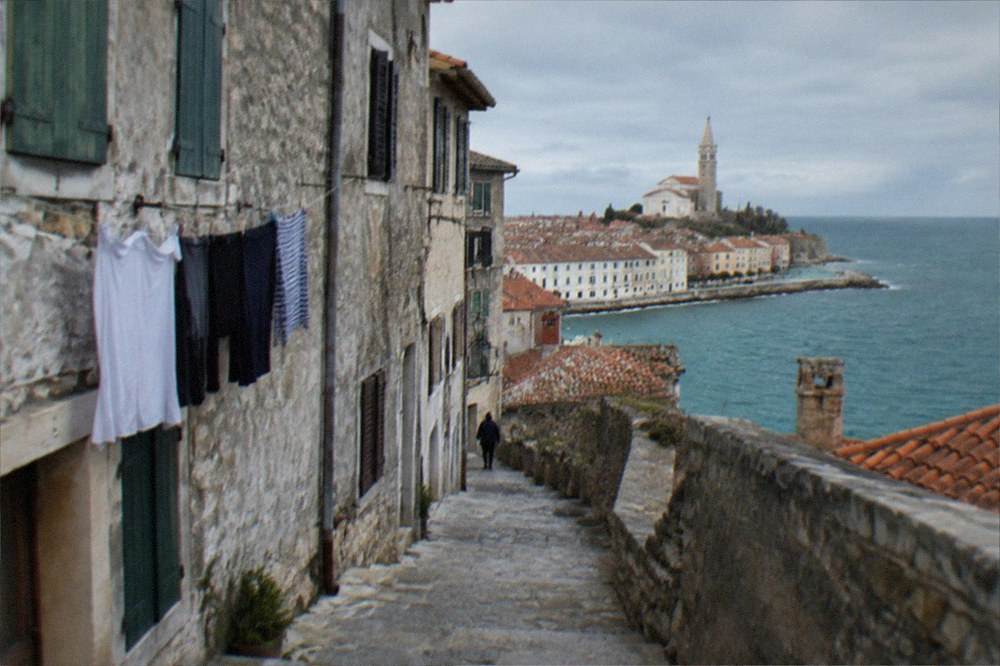 A narrow stone lane in a coastal old town with shuttered windows and hanging laundry.