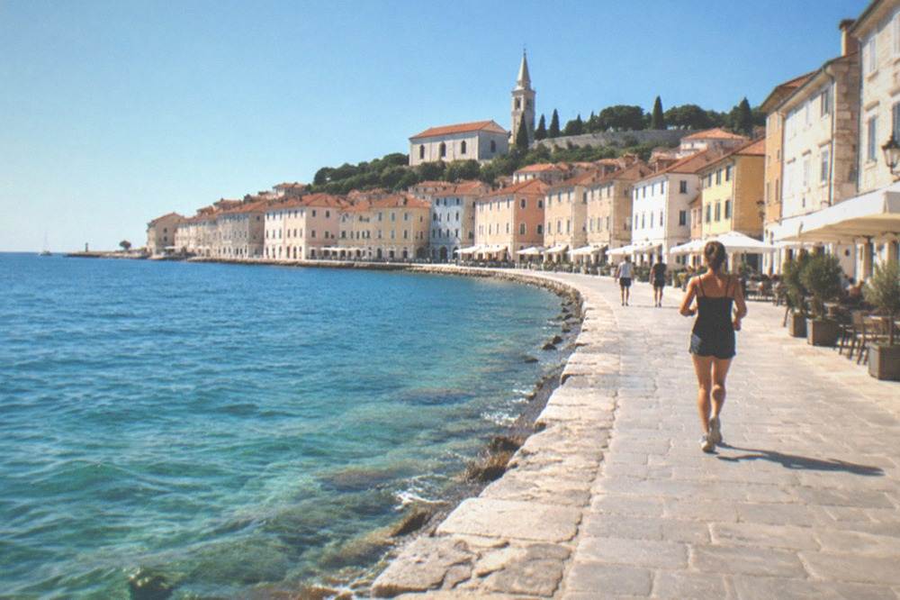 Clear shallow turquoise water lapping a stone sea wall at Piran under a blue sky