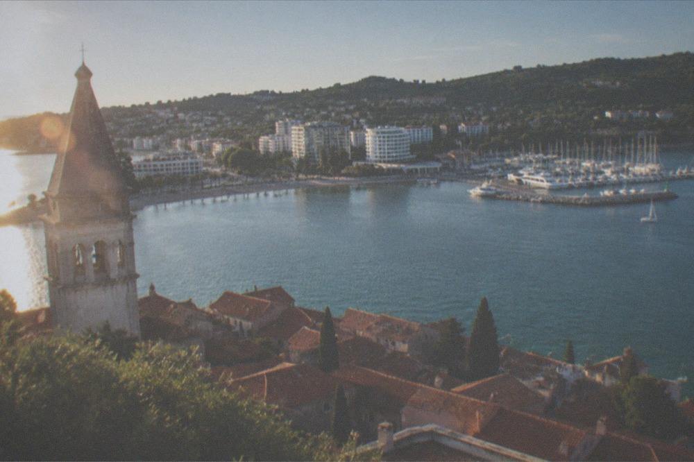 Red-tiled roofs of a small peninsula town seen from a hilltop church tower