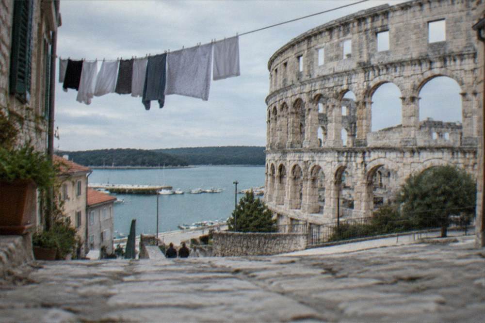 A narrow stone street in a coastal town with laundry hanging between old buildings