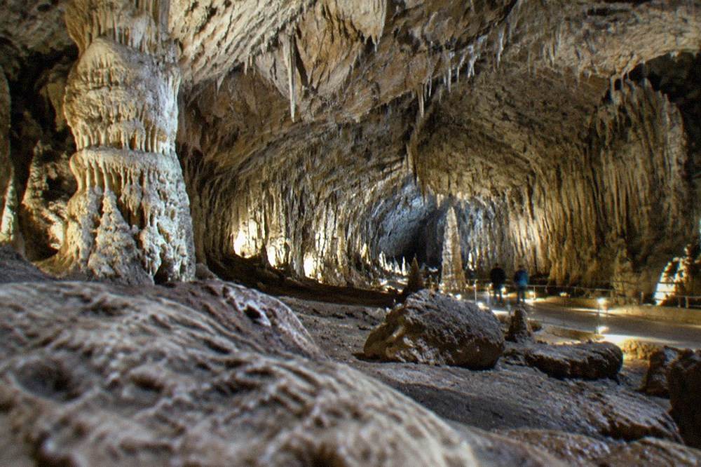 The vast limestone interior of a show cave on the Karst plateau lit for visitors