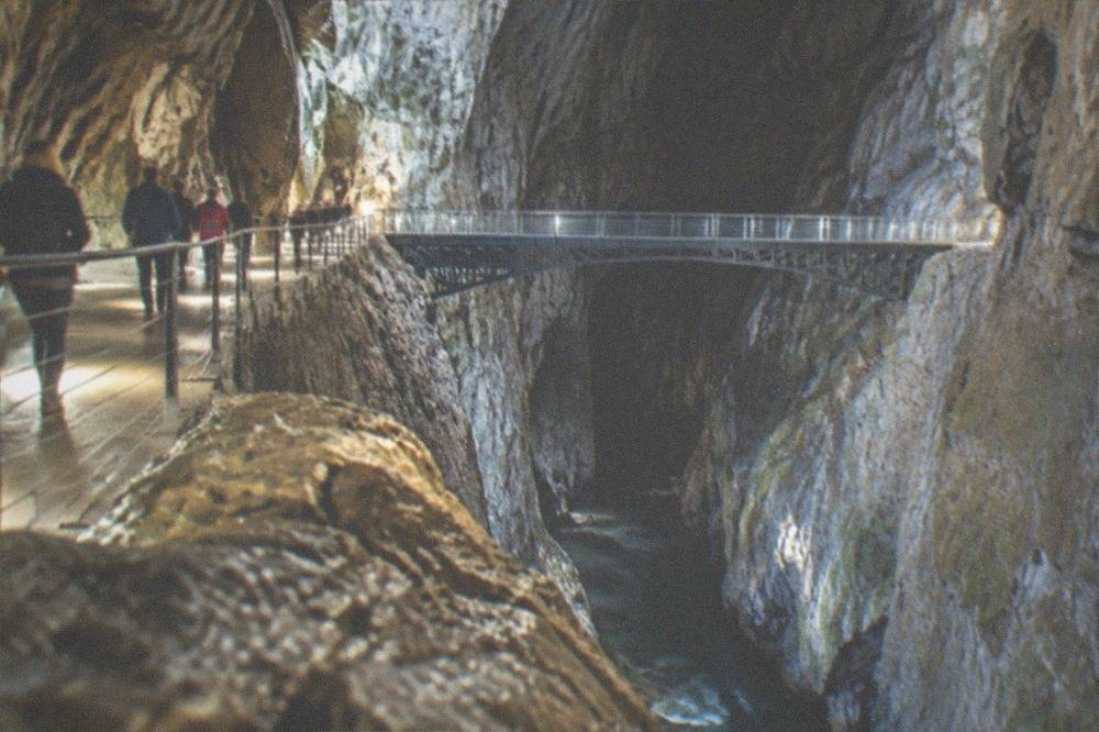 A guided group walking on a lit path inside a large limestone cavern