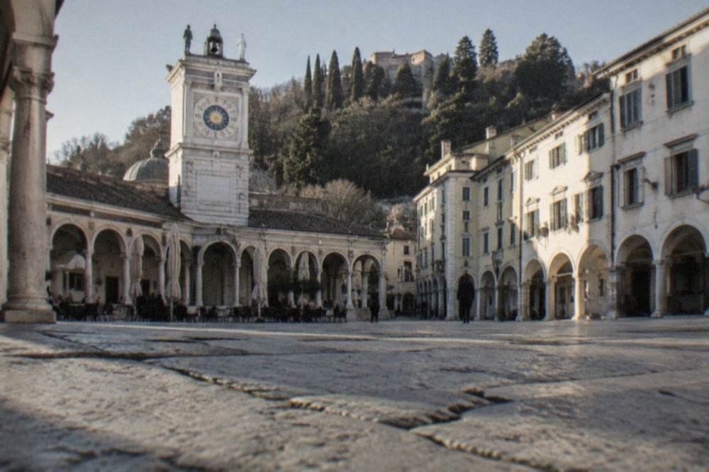 Arcaded square in central Udine with a clock tower and cafe tables under the arches