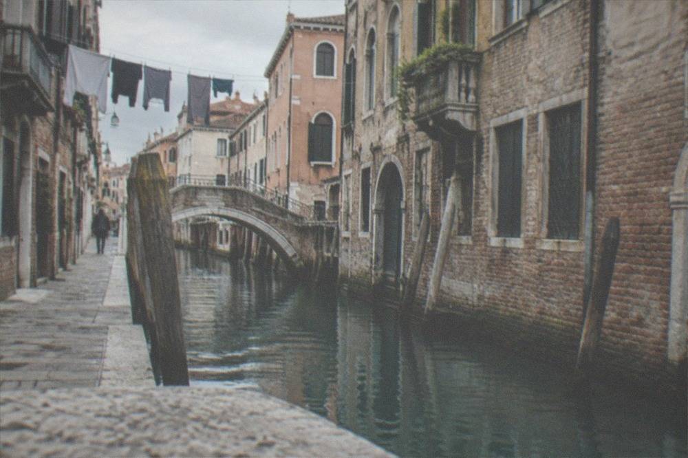 A narrow Venetian backstreet with laundry above and a small canal