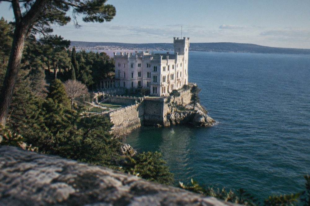 The white facade of Miramare Castle seen from its park above the Gulf of Trieste