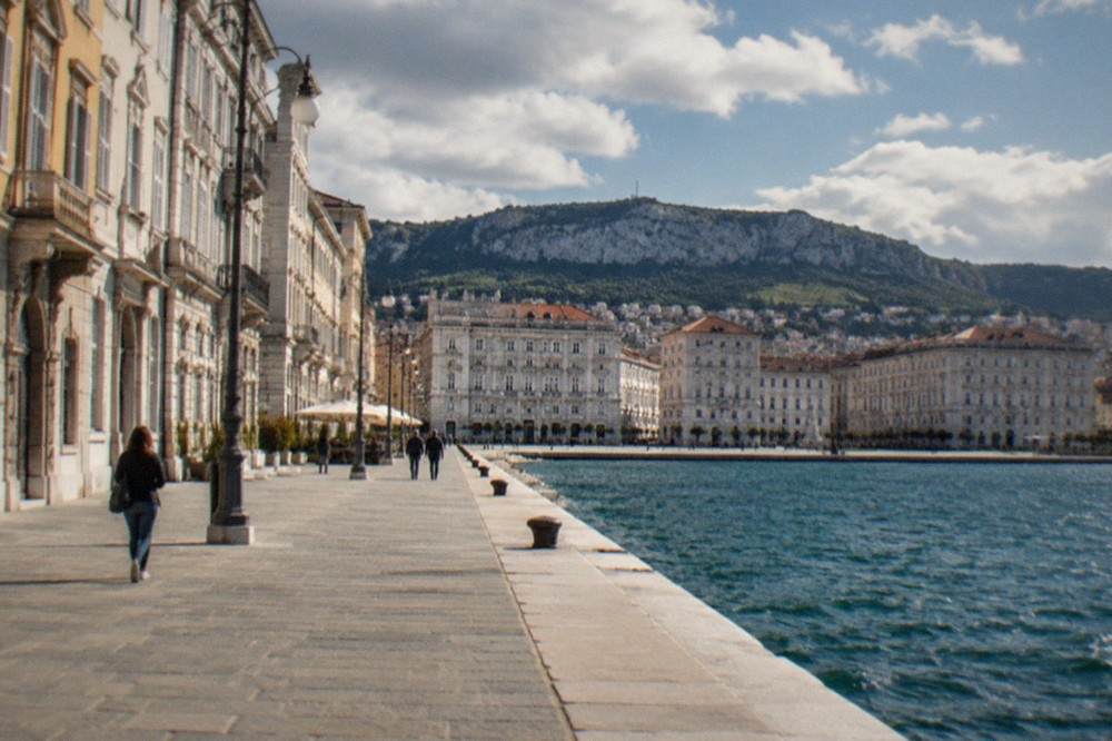 A long level seaside promenade in Trieste with a wide paved walkway beside the Adriatic