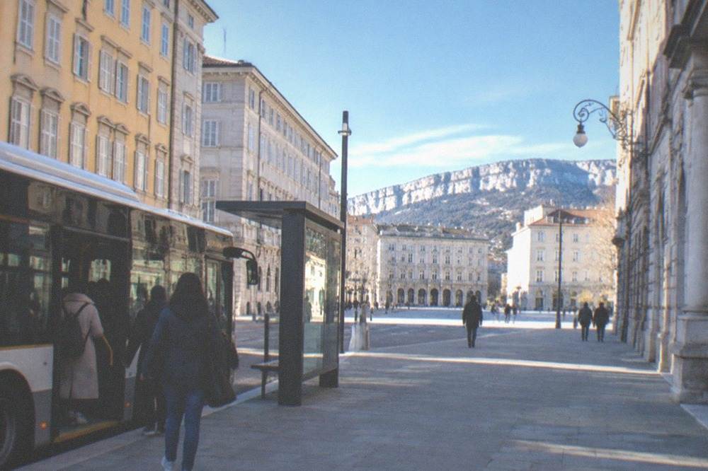 A modern city bus at a stop in Trieste with a low floor and a boarding door