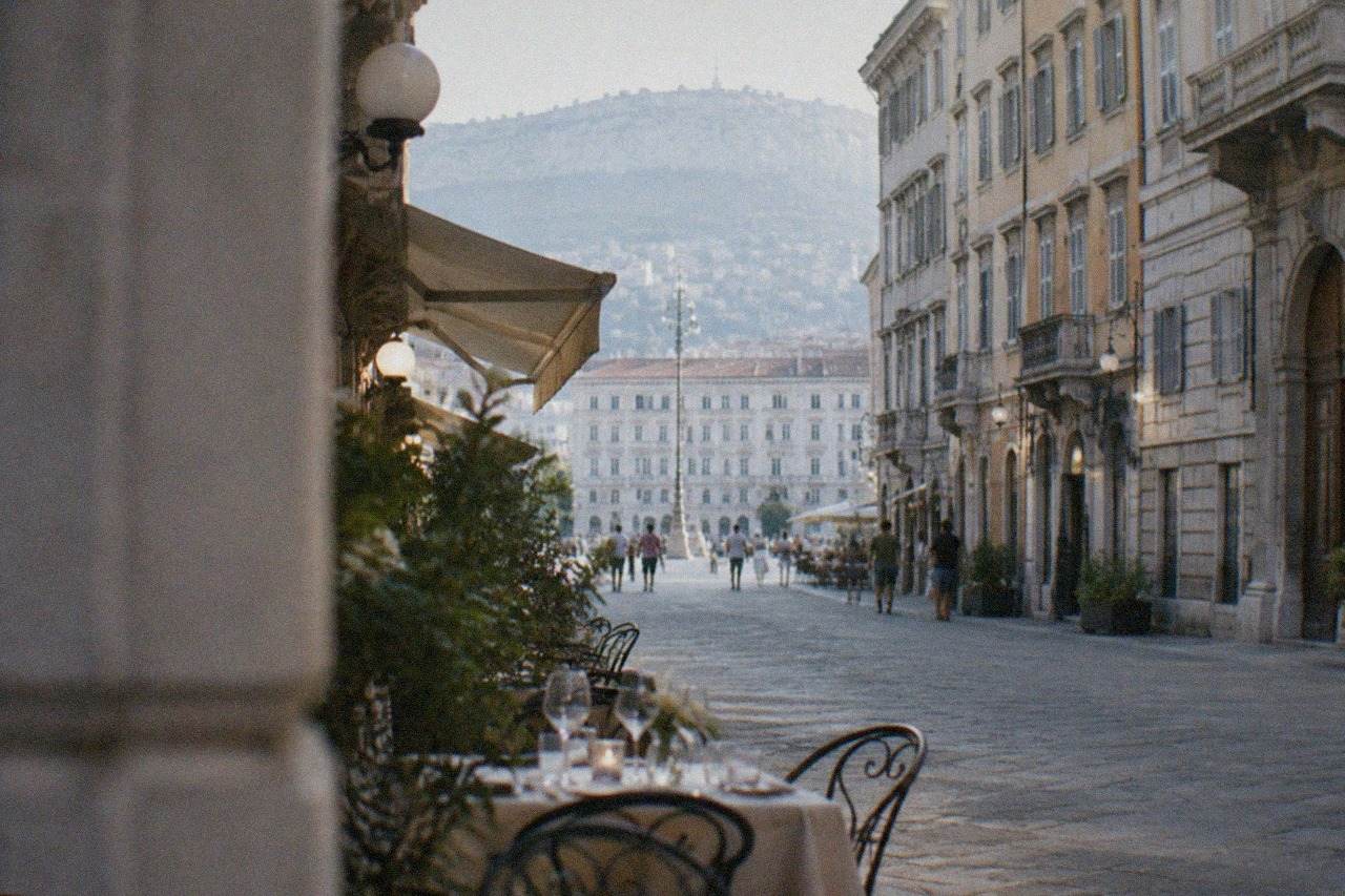 A table set for dinner beside a historic Trieste cafe facade in the evening