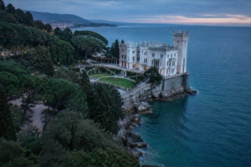 The white cliff face of Miramare Castle above the sea near Trieste with its park in the foreground