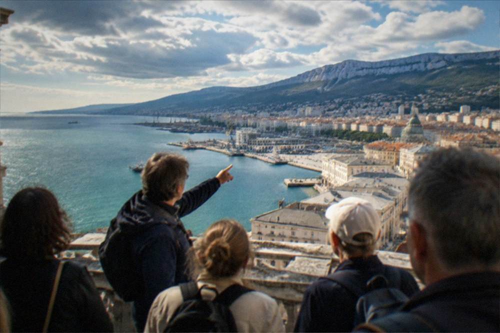 A guided walking group on a terrace above Trieste with the guide pointing out landmarks across the gulf