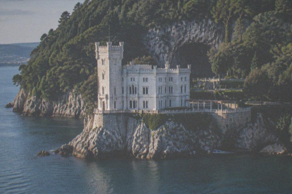 A castle built into a cliff face with a cave mouth behind its walls