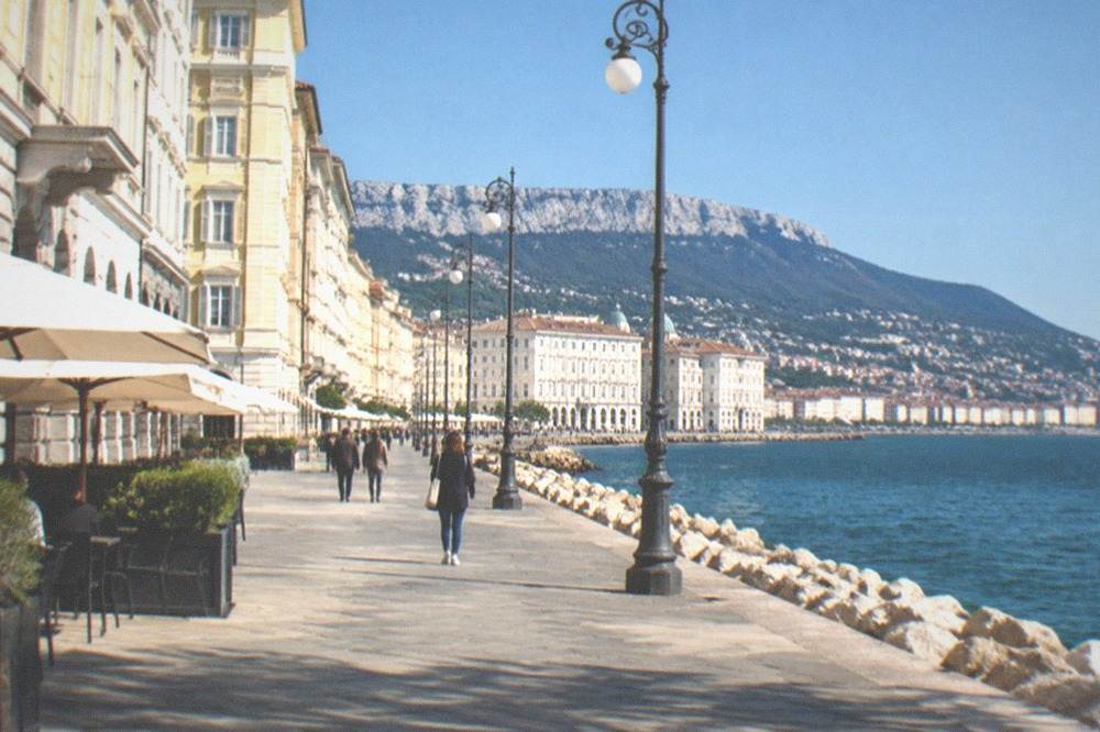 The seafront at Trieste under a clear sky with the coastline curving away