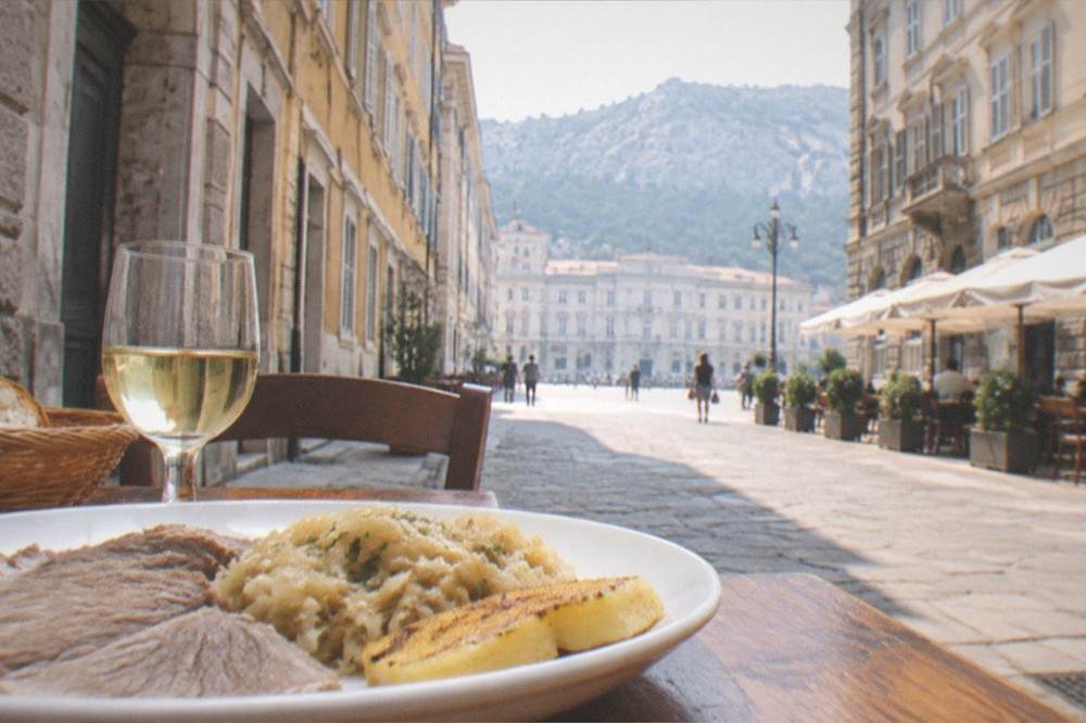 A plate of local Triestine dishes on a wooden table in a small eatery