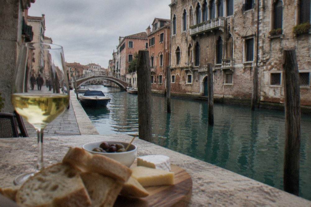A glass of white wine on a stone cellar table with bread and cheese
