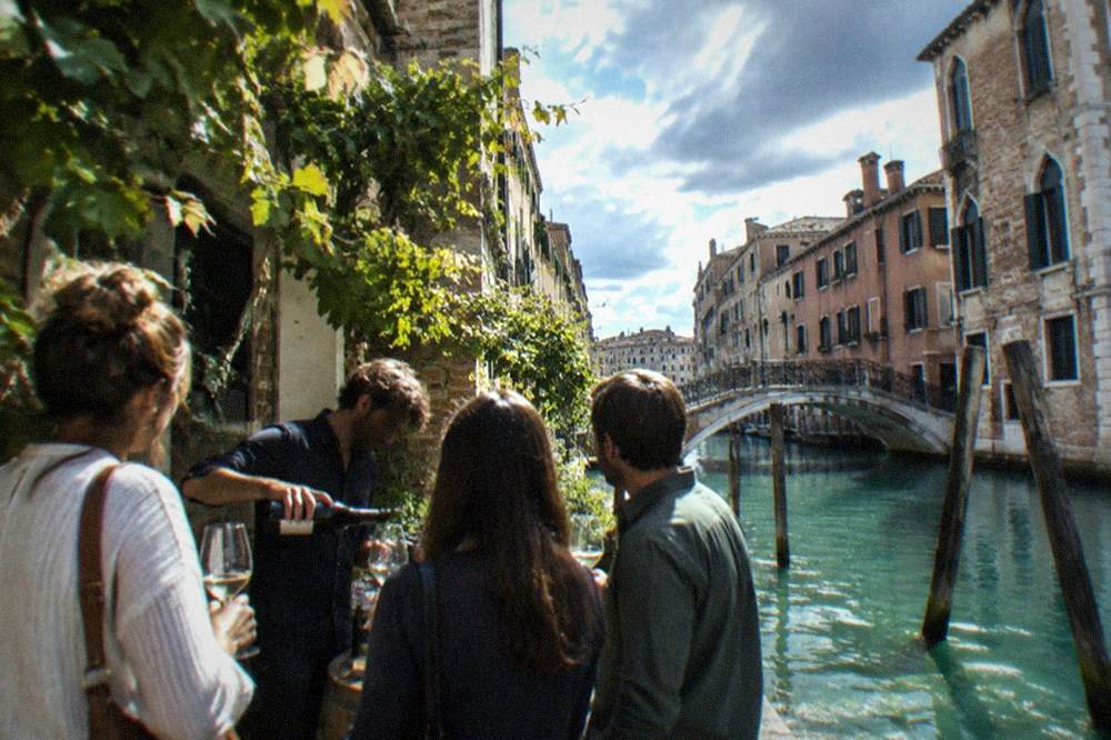 A small group standing among vines while a guide pours wine