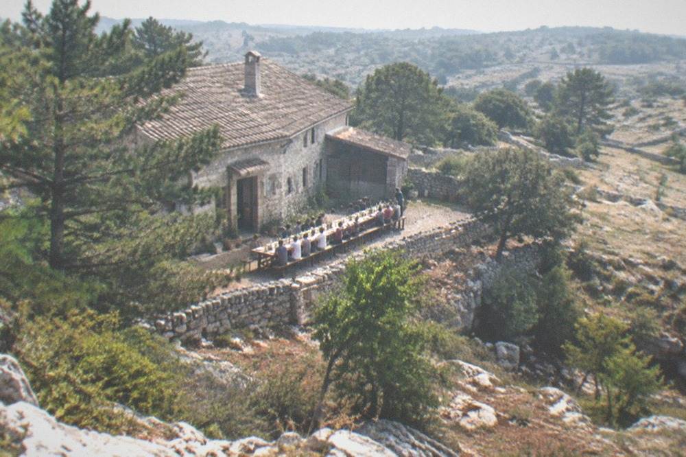 Long wooden tables set for sharing inside a rustic Karst farmhouse