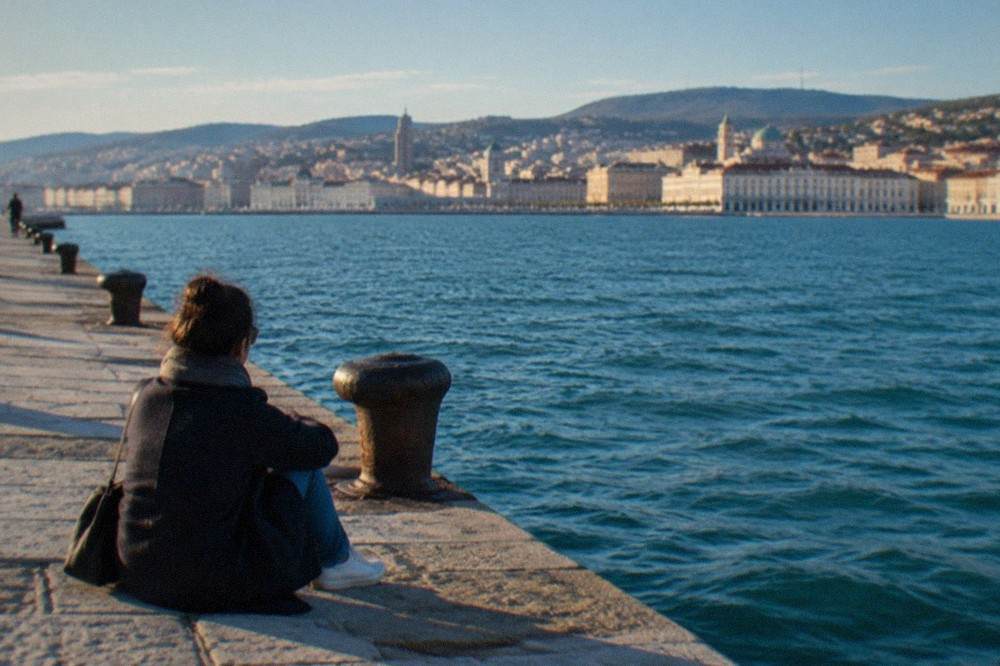 A visitor looking at the sea from Molo Audace on a clear morning