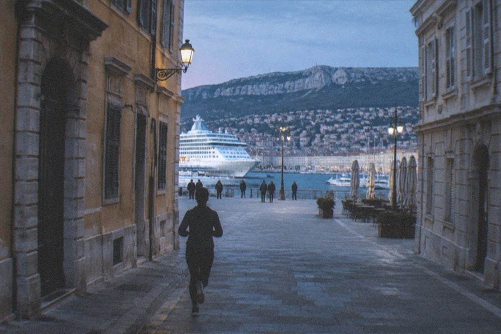Cruise ship and small boats at the Trieste waterfront with the city rising behind the docks