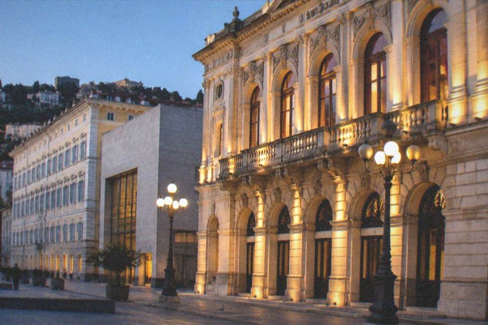 An evening view of a lit theatre facade on a European city street
