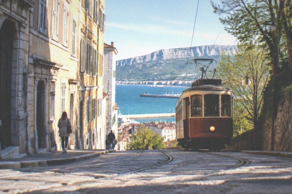 A vintage tram climbing a hillside above the sea toward the Karst village of Opicina