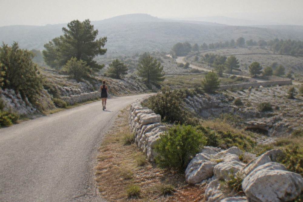 A winding road climbing the limestone slope of the Karst plateau above Trieste with dry stone walls beside it
