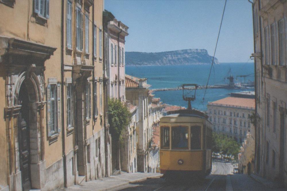 A tram climbing a hillside street above Trieste with the sea in the distance