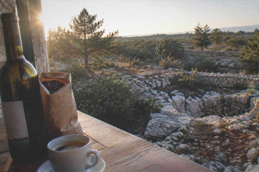 A bottle of local Carso wine and a bag of coffee beans on a wooden counter in Trieste