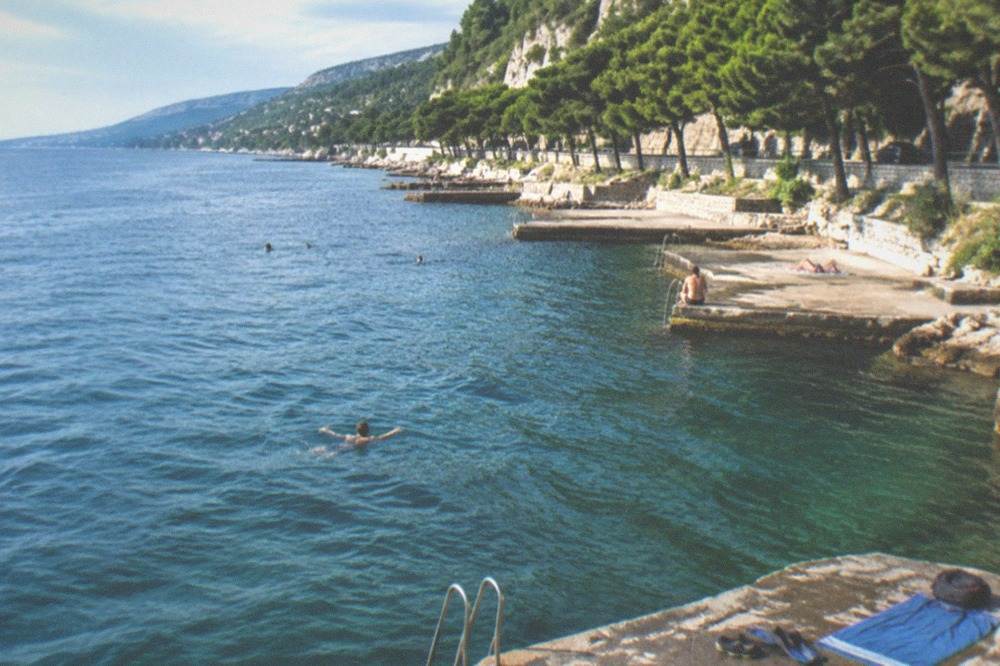 Swimming gear, rock shoes and a towel laid out on a concrete seafront platform beside the sea