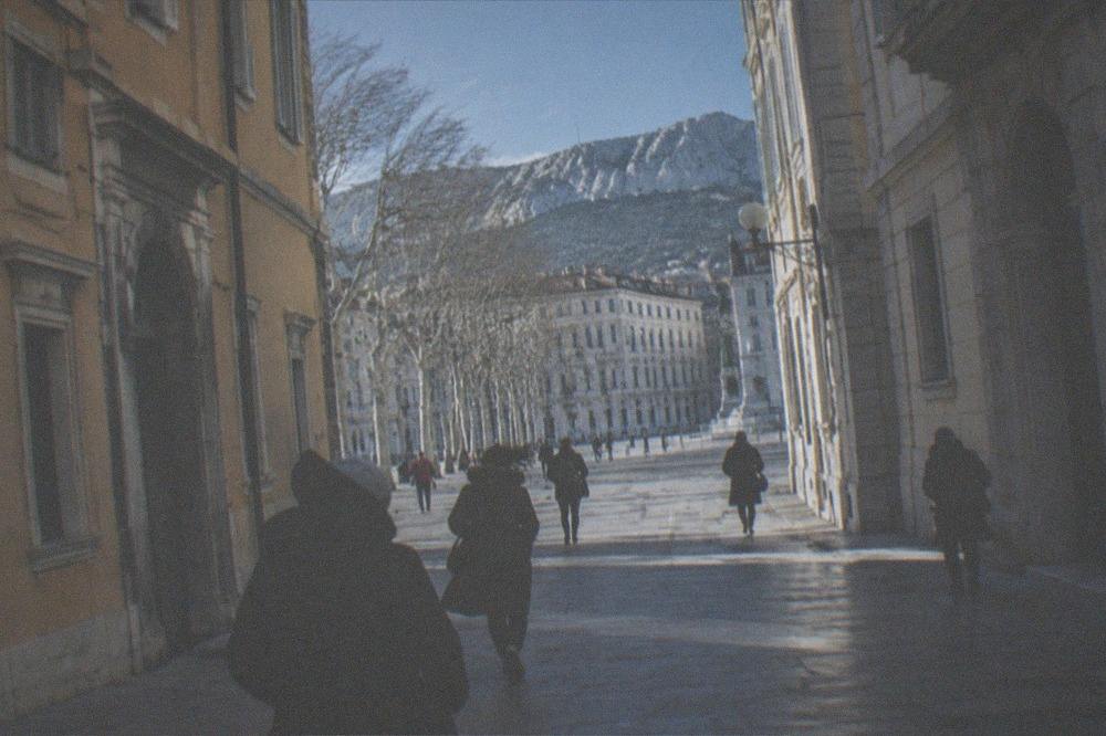 A narrow old-town street in Trieste with tall buildings sheltering the lane from the wind