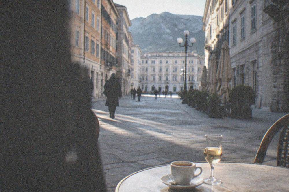 An evening espresso and a small glass of liqueur on a marble café table in Trieste