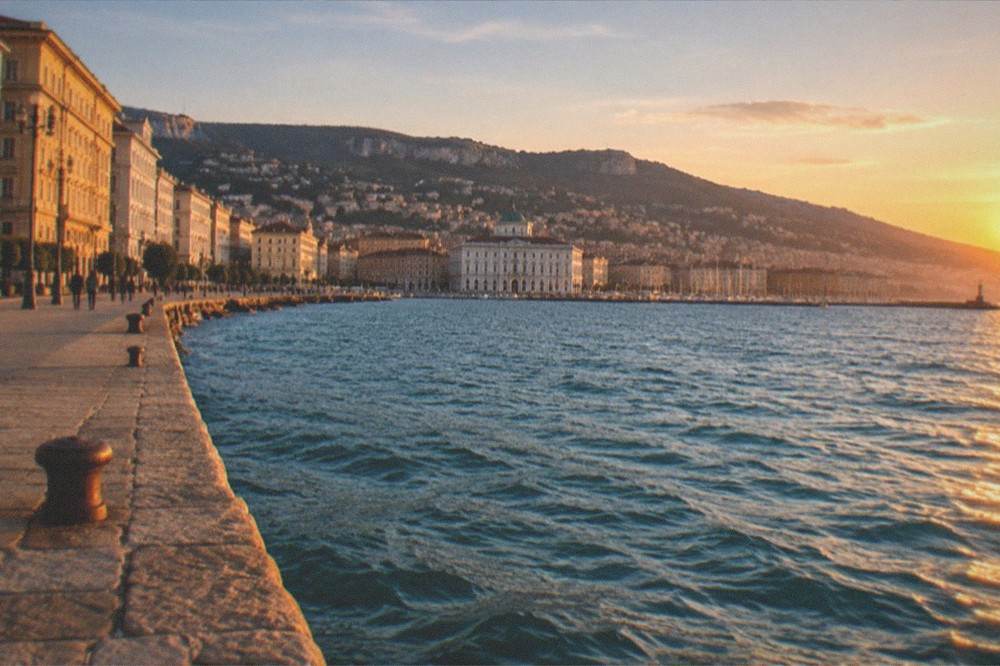 An evening view over the Gulf of Trieste from the seafront with the city lights beginning to show along the shore