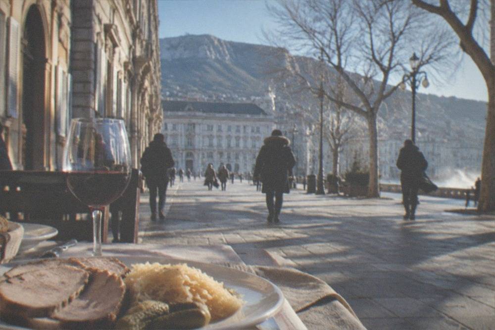 A table of Trieste buffet dishes with sliced pork, sauerkraut and a glass of red wine