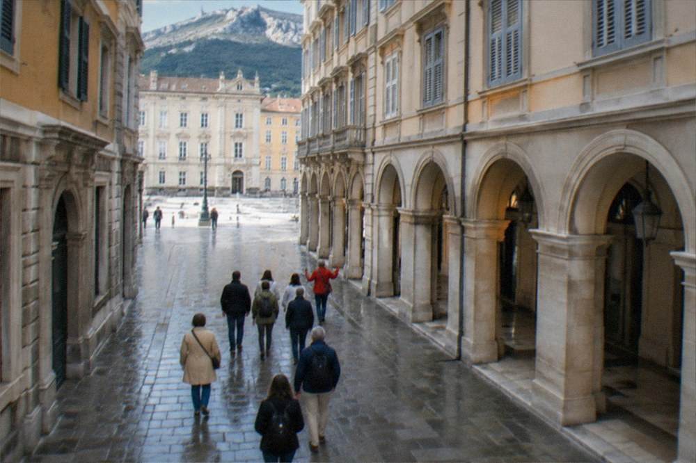 A small group of visitors following a guide along an elegant arcaded street in central Trieste
