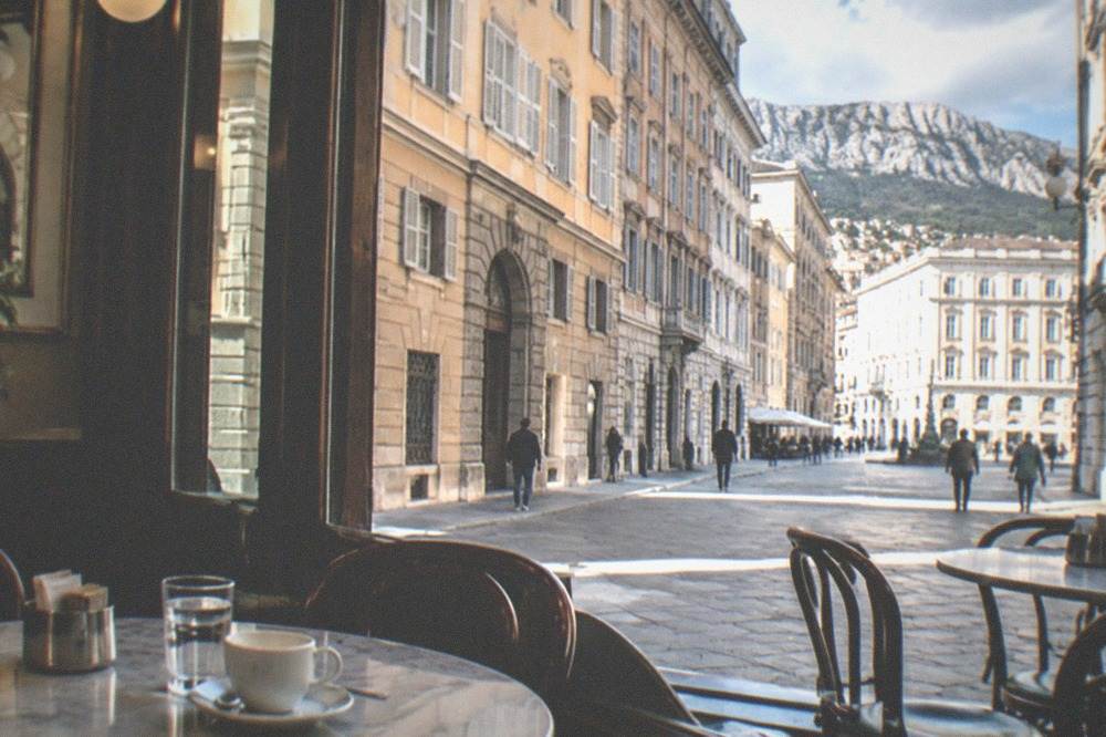 A historic Trieste cafe interior with marble tables, newspapers and waiters in white jackets