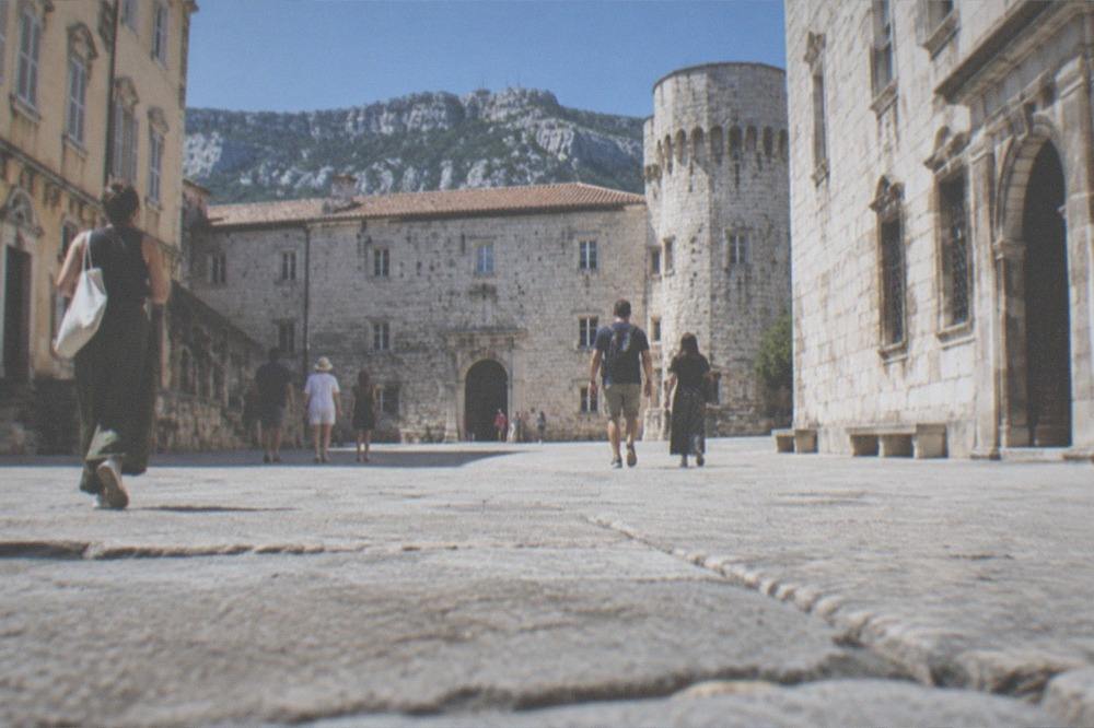 Visitors walking through the stone courtyard of a historic castle museum on a bright afternoon