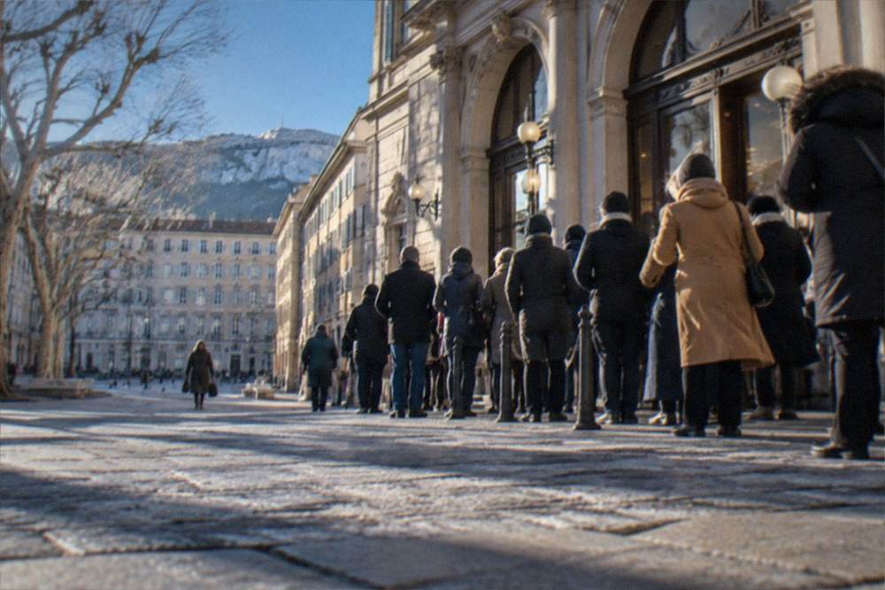 People queueing outside an ornate neo-classical cinema building on a winter evening