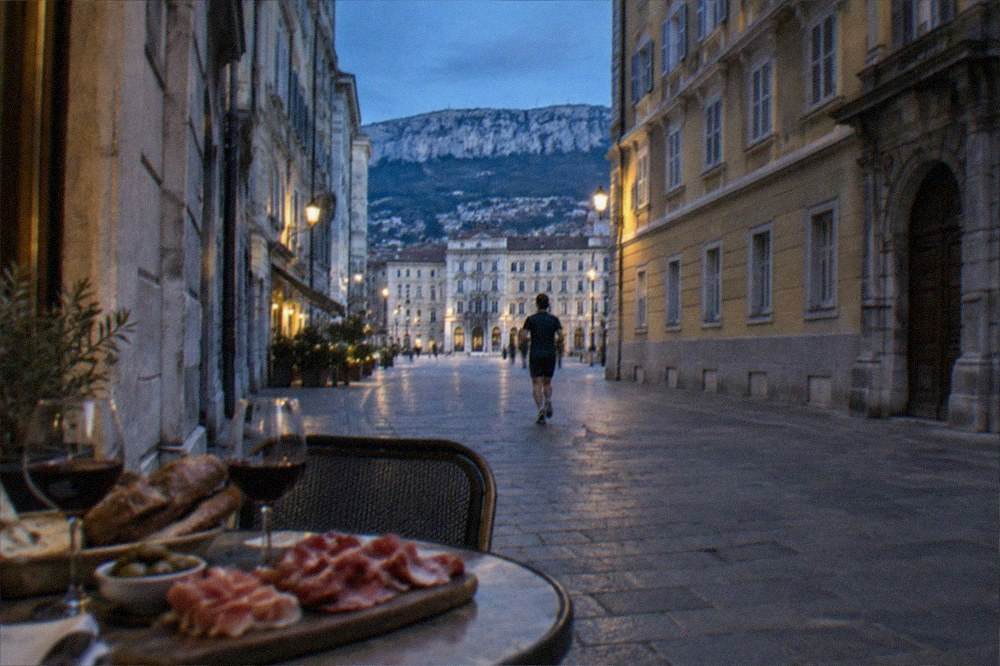 A table with regional cured meats, bread and glasses of red wine in a small Trieste eatery