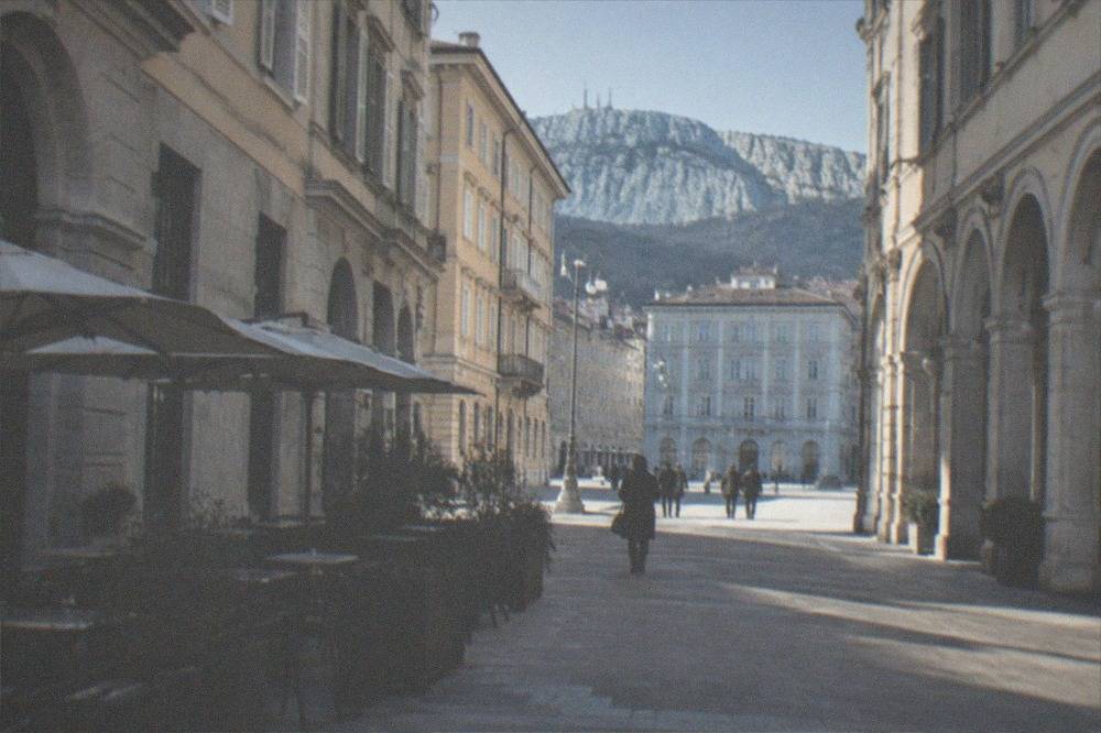 A neoclassical street in central Trieste with cafés and arcades
