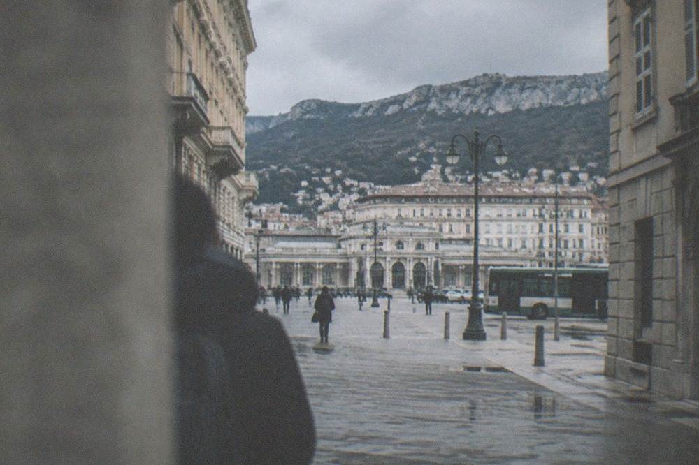 A train station forecourt in Trieste with the city grid beyond