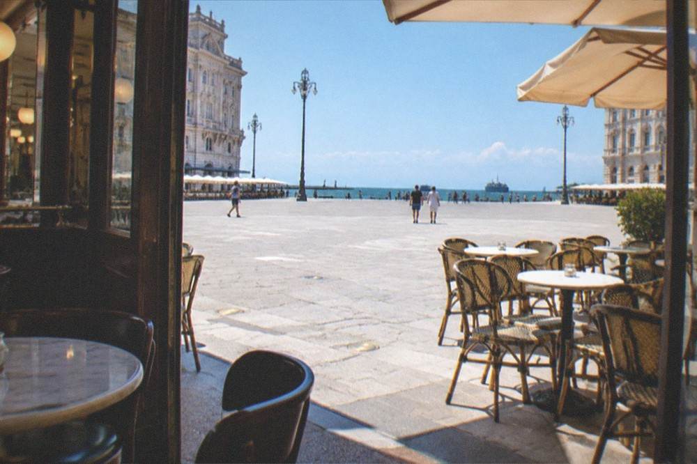 The historic caffè interiors and evening lights of Piazza Unità d'Italia in Trieste, Italy